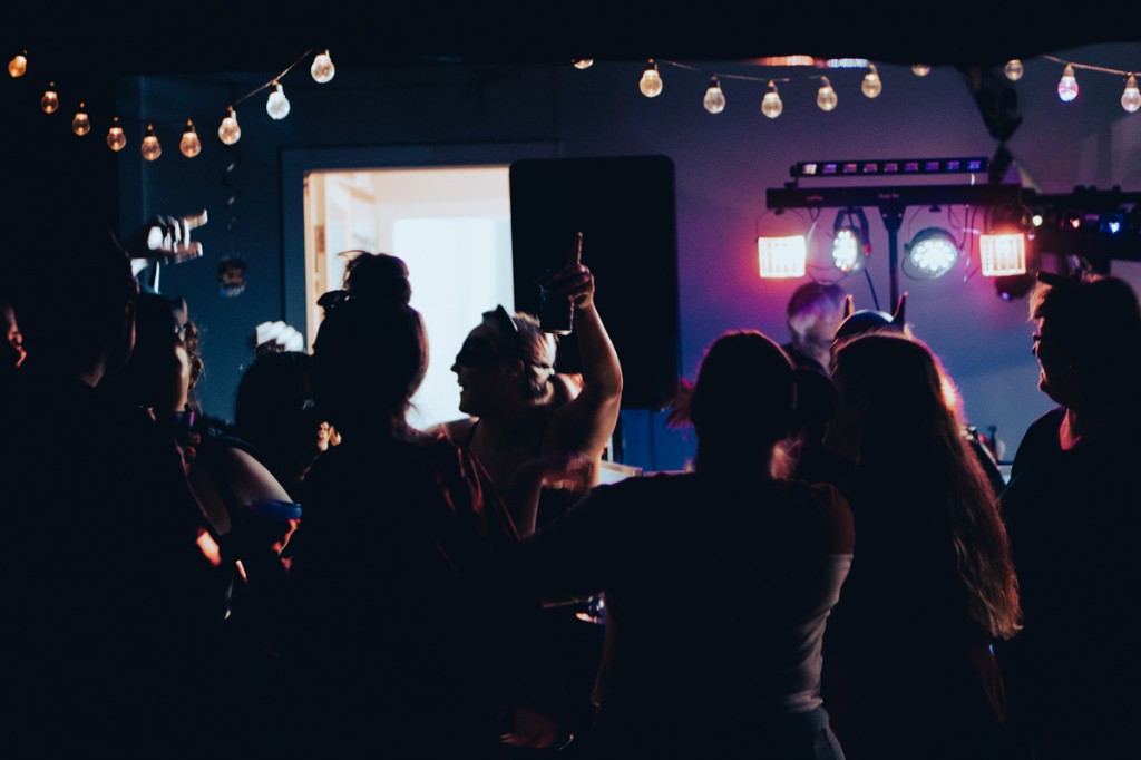 Milestone birthday guests dancing in front of a DJ booth with party lighting